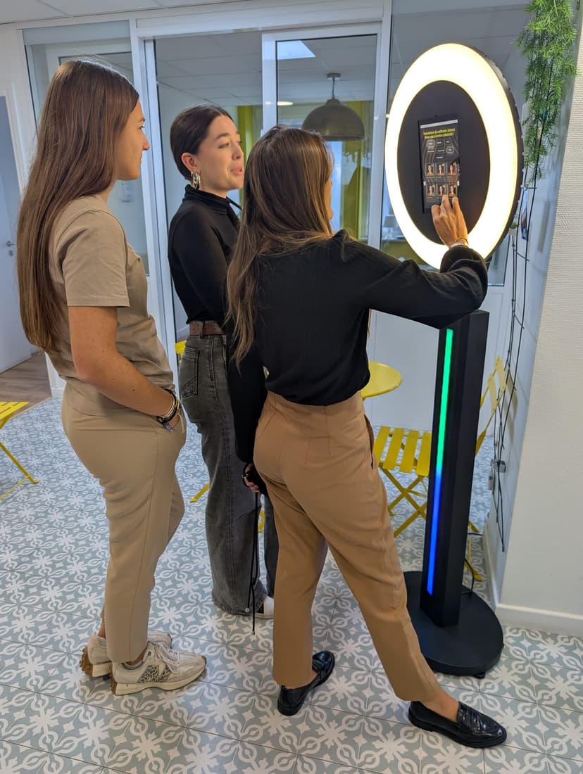 Employés utilisant le photobooth IA dans hall d'entreprise